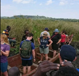 A group of tourists preparing for a boat tour through the dense papyrus reeds of Mabamba Swamp. This area, known for its rich birdlife, including the rare Shoebill stork, attracts birdwatchers and nature enthusiasts seeking an immersive experience in Uganda's wetlands.